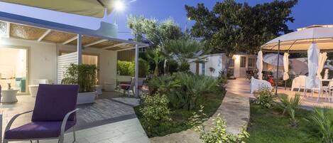 A patio area with a chair, a small garden, and a covered seating area.