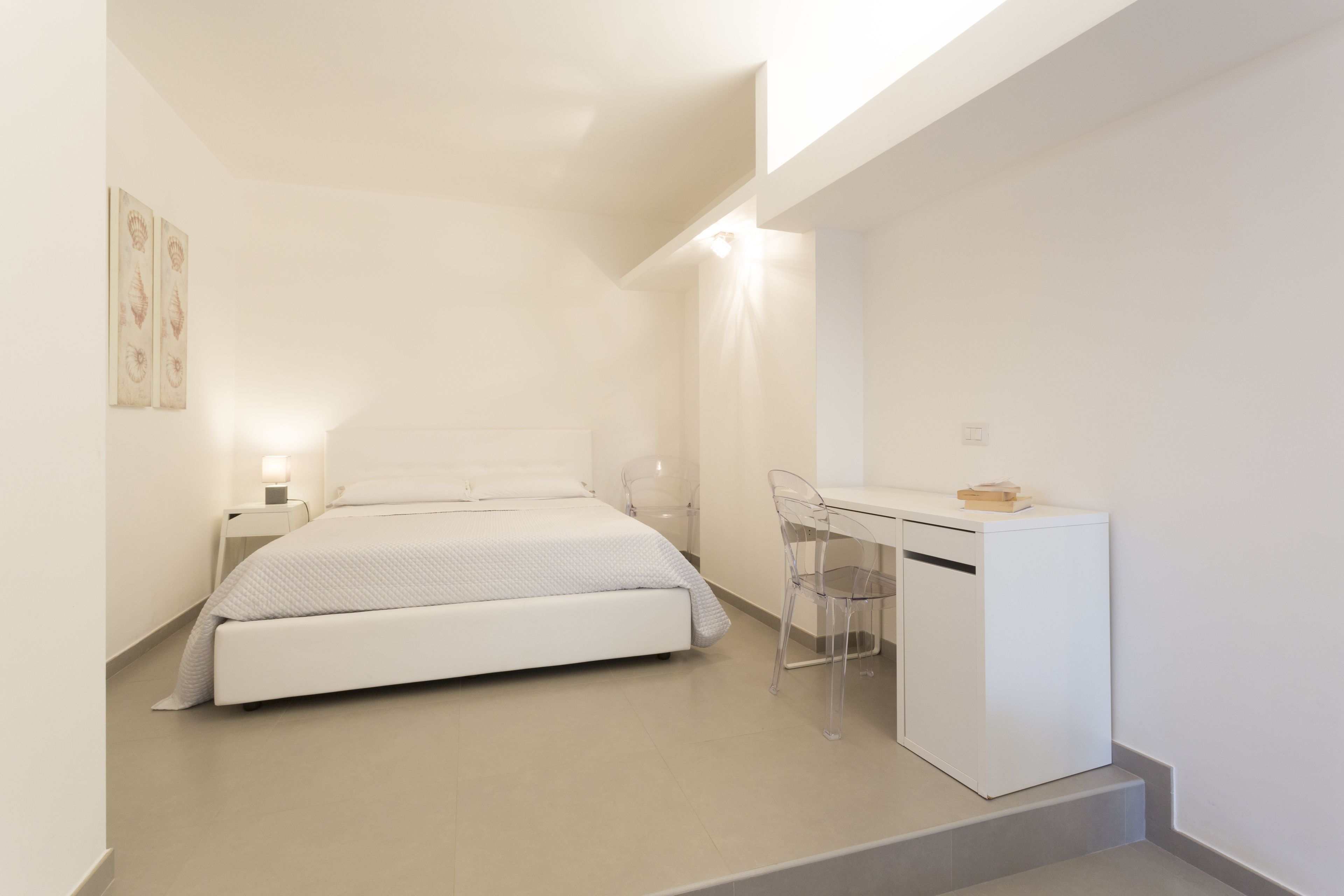 Un dormitorio moderno con cama, mesita de noche y escritorio con silla.