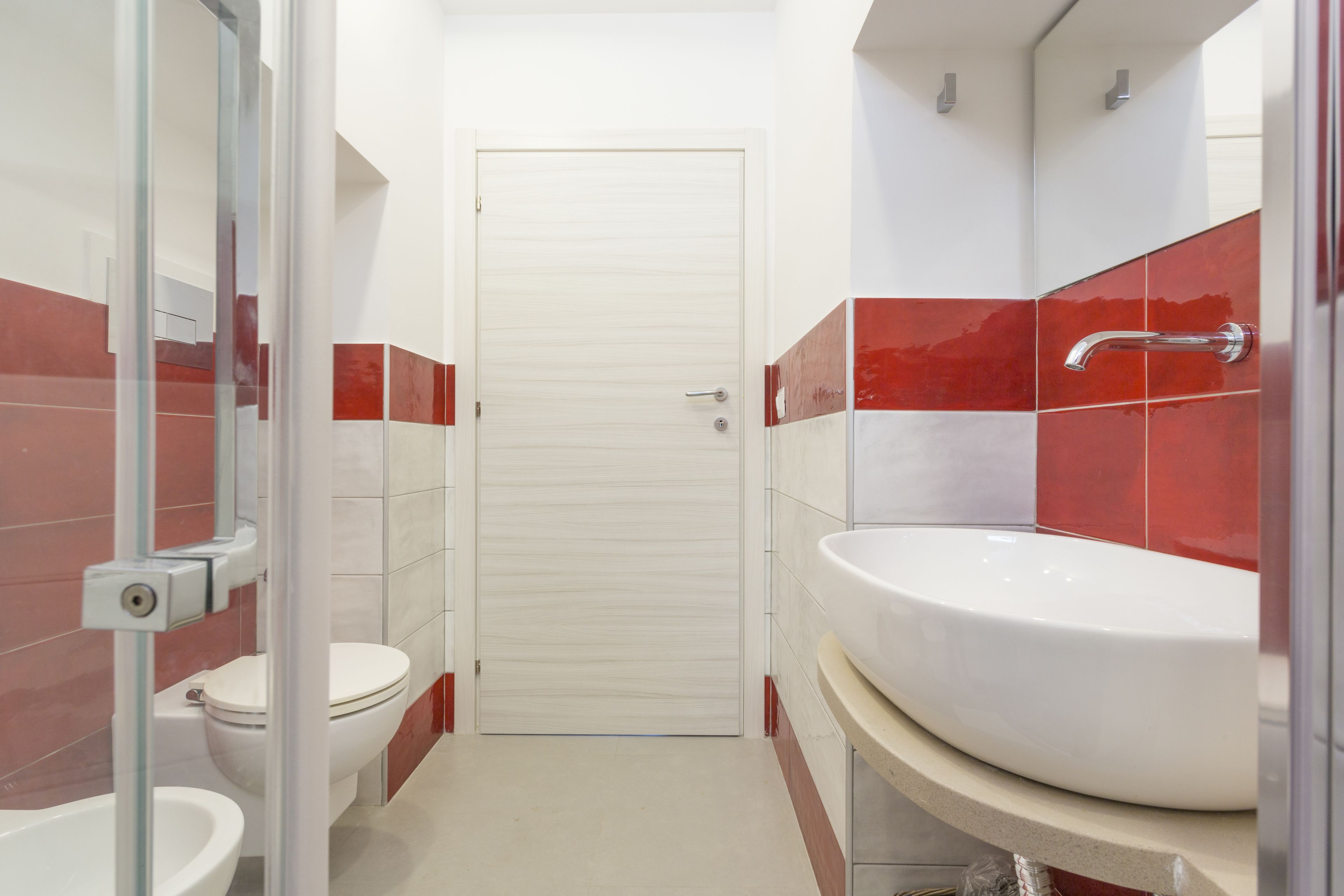 A bathroom with a toilet, sink, and glass shower enclosure.