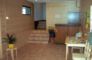 Een hal met een receptiebalie, een trap en een eetgedeelte met stoelen en een tafel.