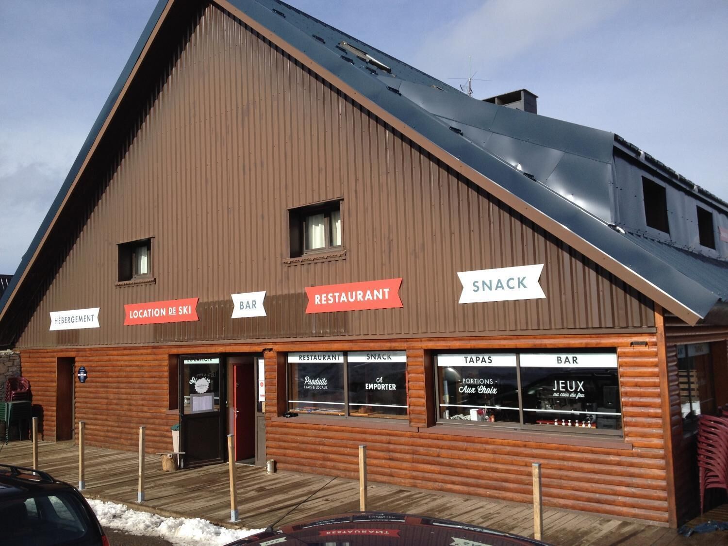 Een houten gebouw met borden voor een bar, restaurant en snacks.