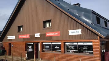 Een houten gebouw met borden voor een bar, restaurant en snacks.