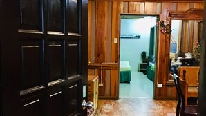 L’entrée d’une chambre d’hôtel, avec une porte en bois, une plaque indiquant le numéro de la chambre, un sol en marbre et une vue sur l’intérieur de la chambre.