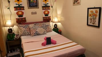 Un dormitorio ordenado con cama, almohadas y dos lámparas fijadas a la pared.