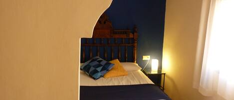 A bedroom with a bed, a nightstand, and a wall with a circular design.