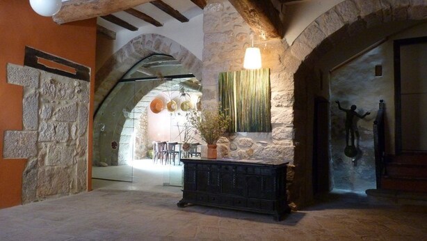 A rustic interior with stone walls, wooden beams, and a stone fireplace. - Cal Maginet Hotel (Vilaverd)