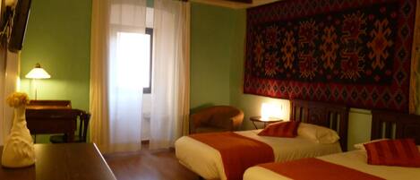 A room with two beds, a desk, a lamp, and a tapestry on the wall.