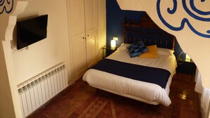 A bedroom with a bed, a television mounted on the wall, a radiator, and a door. - Cal Maginet Hotel (Vilaverd)