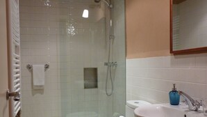 A bathroom with a glass-enclosed shower, a toilet, and a sink with a mirror above it. - Cal Maginet Hotel (Vilaverd)