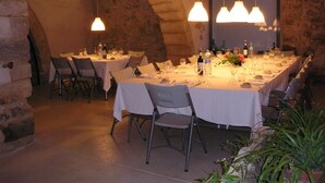 A restaurant with stone walls and hanging pendant lights. Tables are set with white tablecloths and chairs. - Cal Maginet Hotel (Vilaverd)