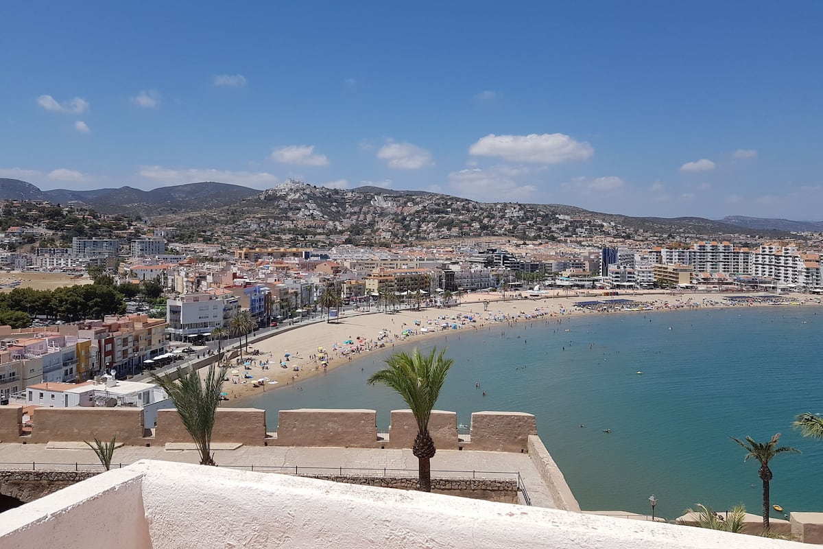 A coastal cityscape with a beach, buildings, and a mountain in the background.