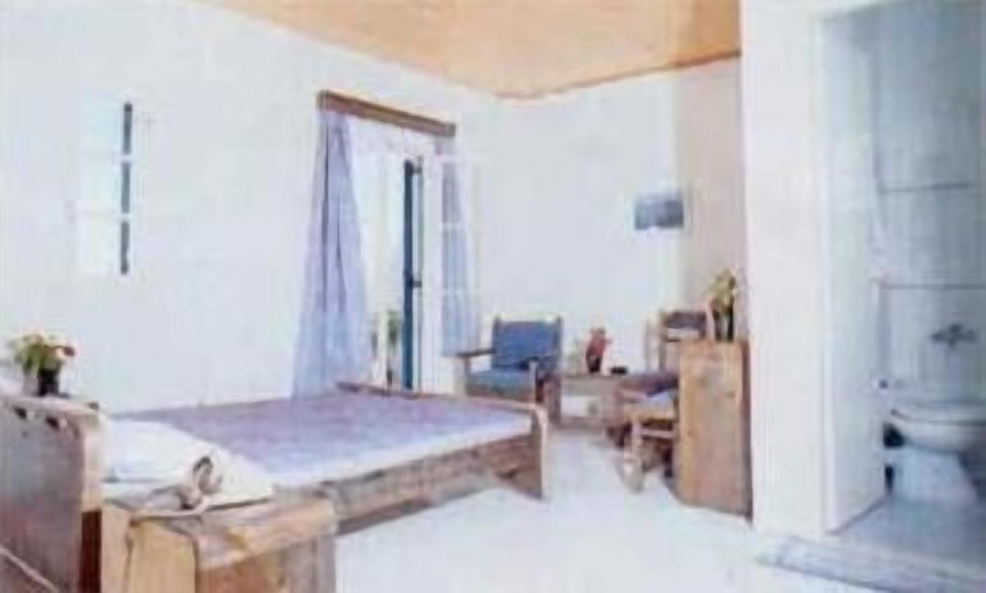 A room with a bed, a desk, and a chair. There is a window with curtains and a door.