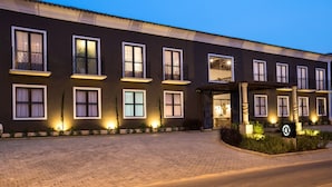 A hotel with multiple balconies, a well-lit entrance, and a paved driveway. - Pousada Armazem 26 (Tiradentes)