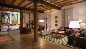 A spacious living area with a fireplace, a sofa, a coffee table, and a dining area with a table and chairs. - Pousada Armazem 26 (Tiradentes)