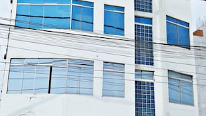 A multi-story building with large windows and a sign on the facade. - Hospedaje Harjeny (Trujillo)