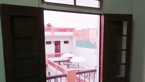 An open door to a balcony with outdoor seating and a view of buildings in the background. - Gran Hotel (Arequipa)