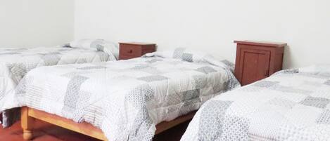 Two single beds with wooden frames and matching nightstands, a red floor, and a plain white wall with a painting.