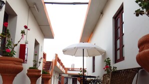 A courtyard with terracotta planters, a table with chairs, and a white umbrella. - Gran Hotel (Arequipa)