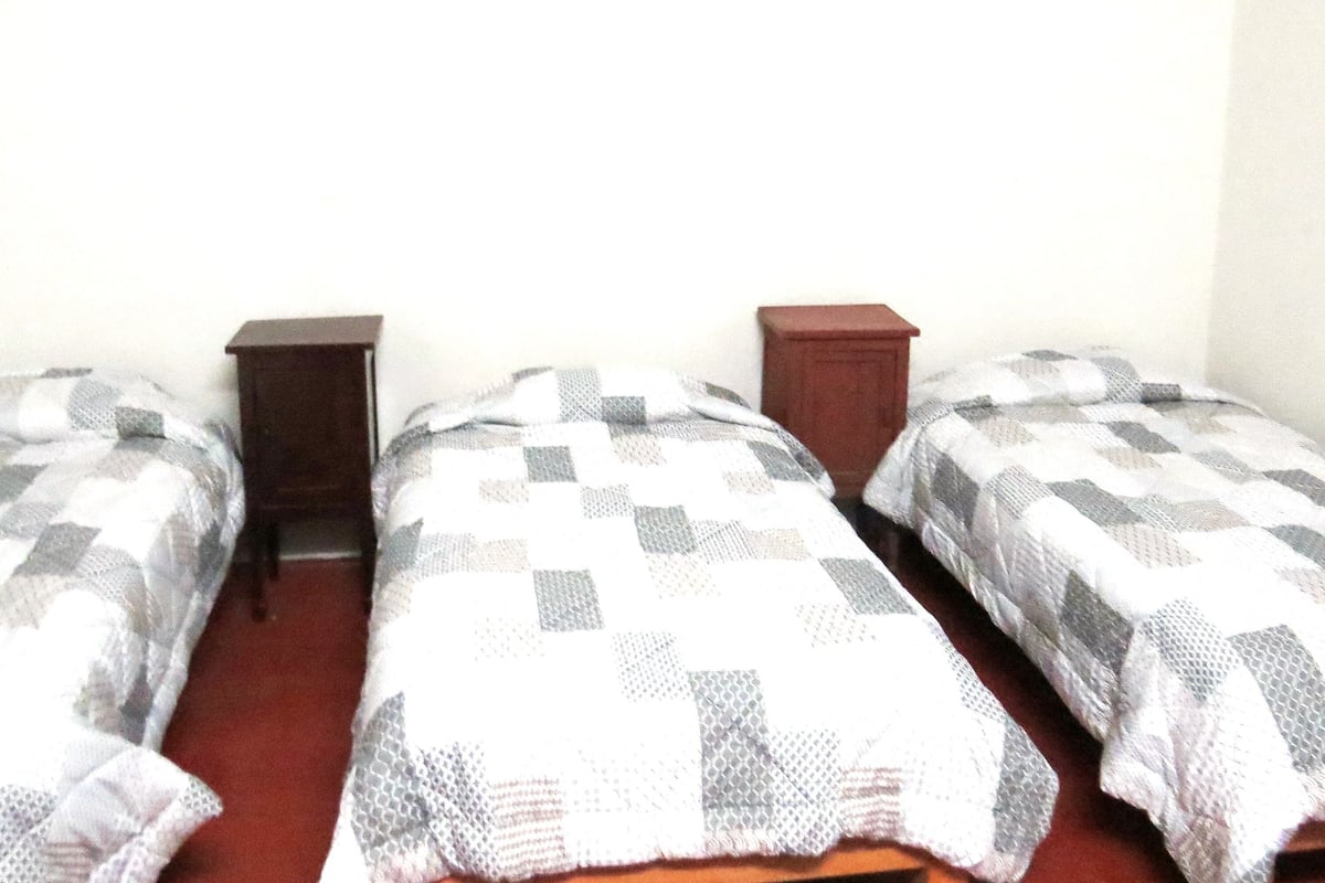 A room with two single beds, each with a checkered blanket and wooden headboards.
