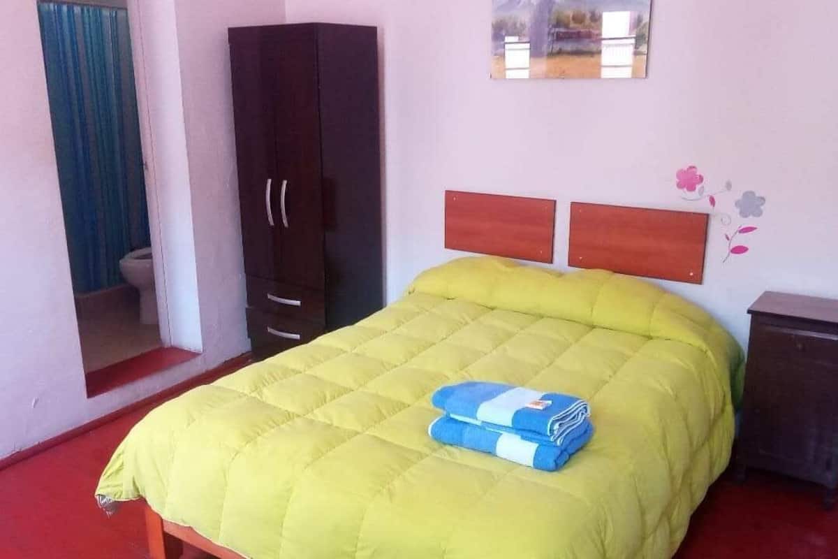A room with a bed, a wardrobe, and a small cabinet.