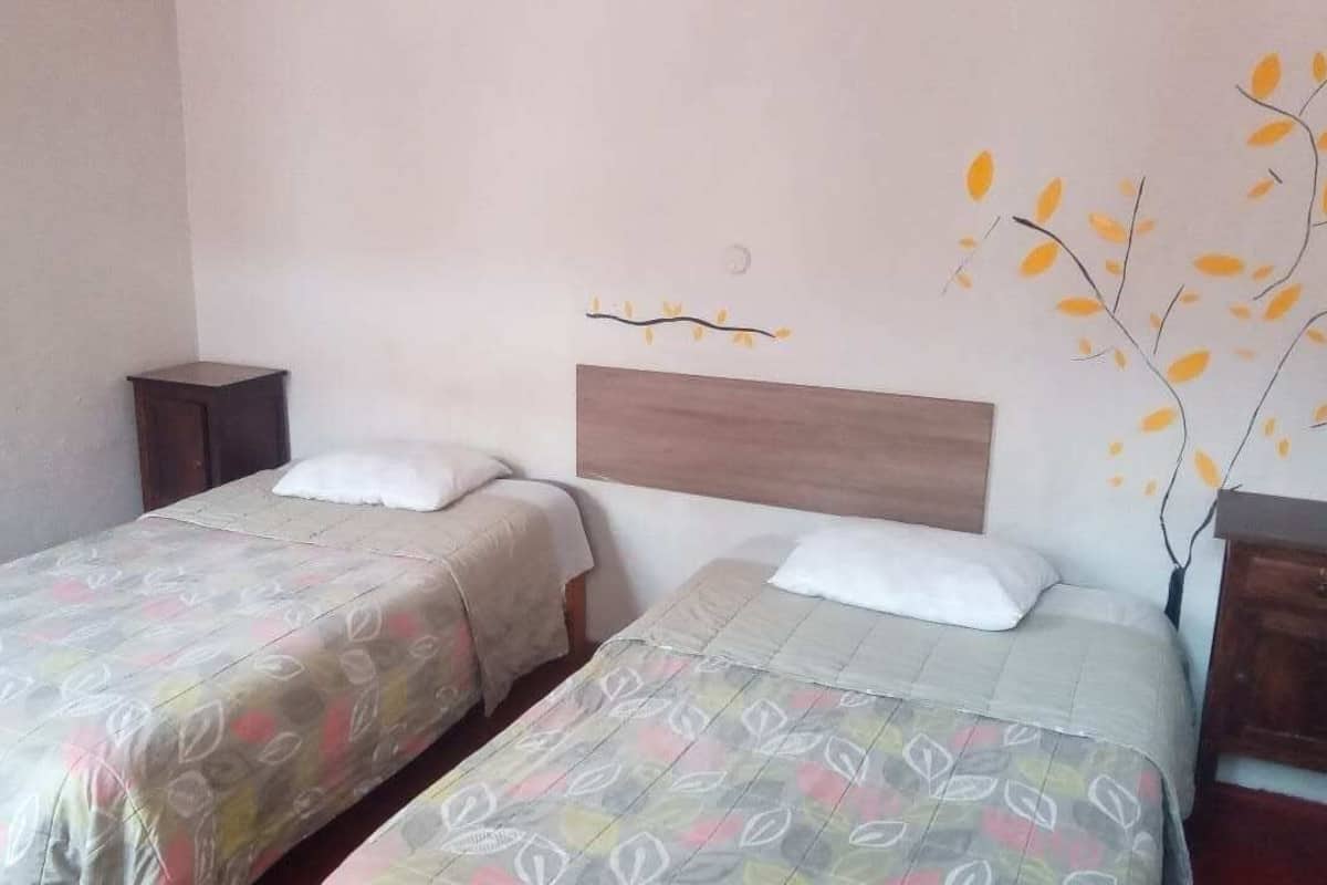 A bedroom with two beds, each with a headboard and a bedside table.
