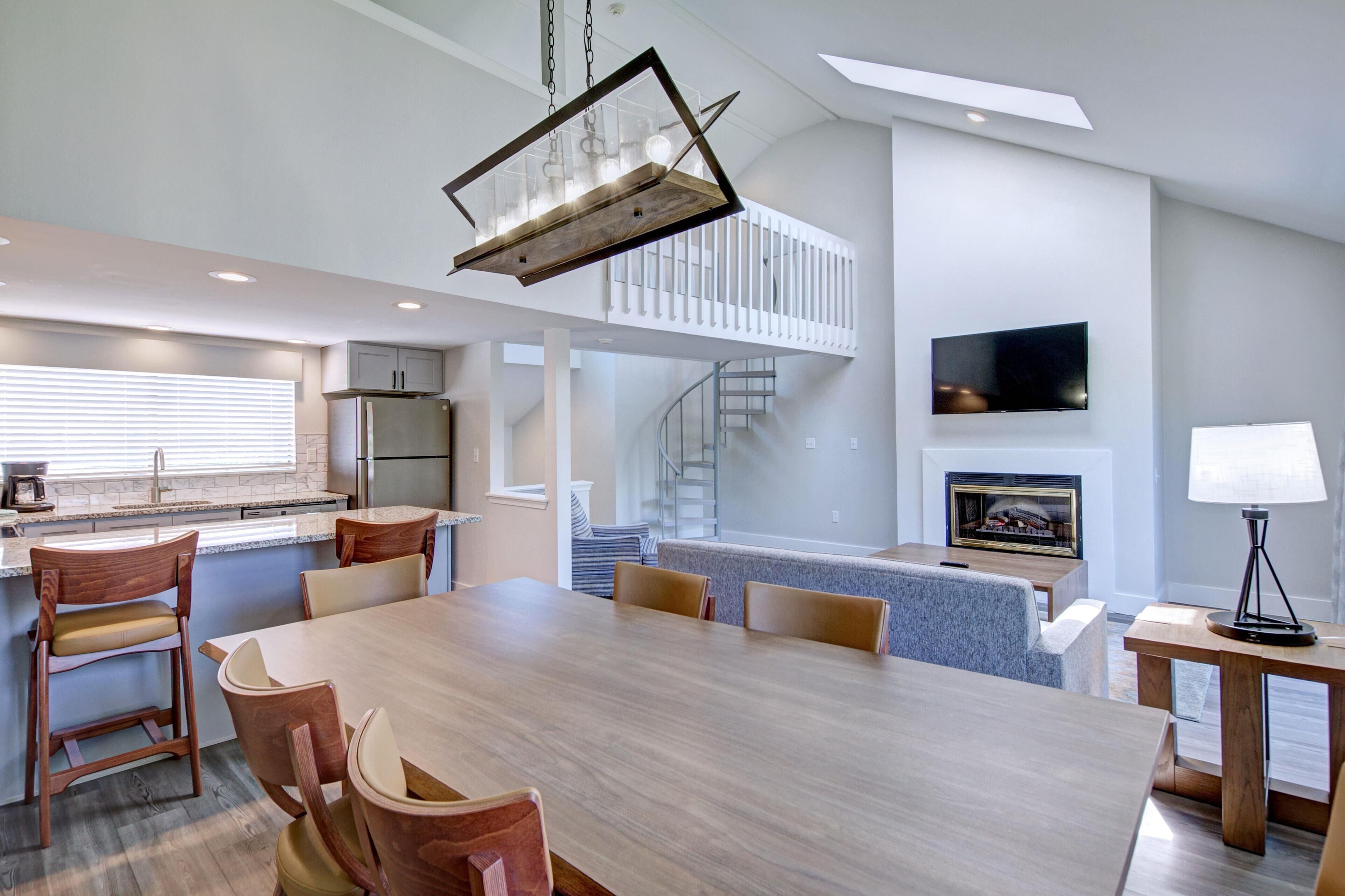 A modern kitchen with a dining area, built-in appliances, and a staircase leading to an upper level.
