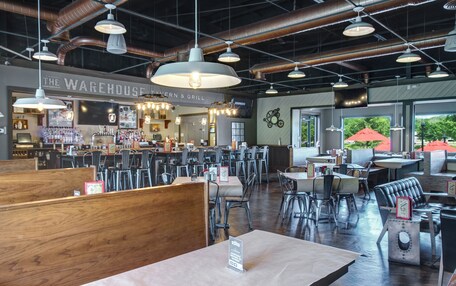 A spacious restaurant with high ceilings, exposed ductwork, and a variety of seating options including booths and tables.