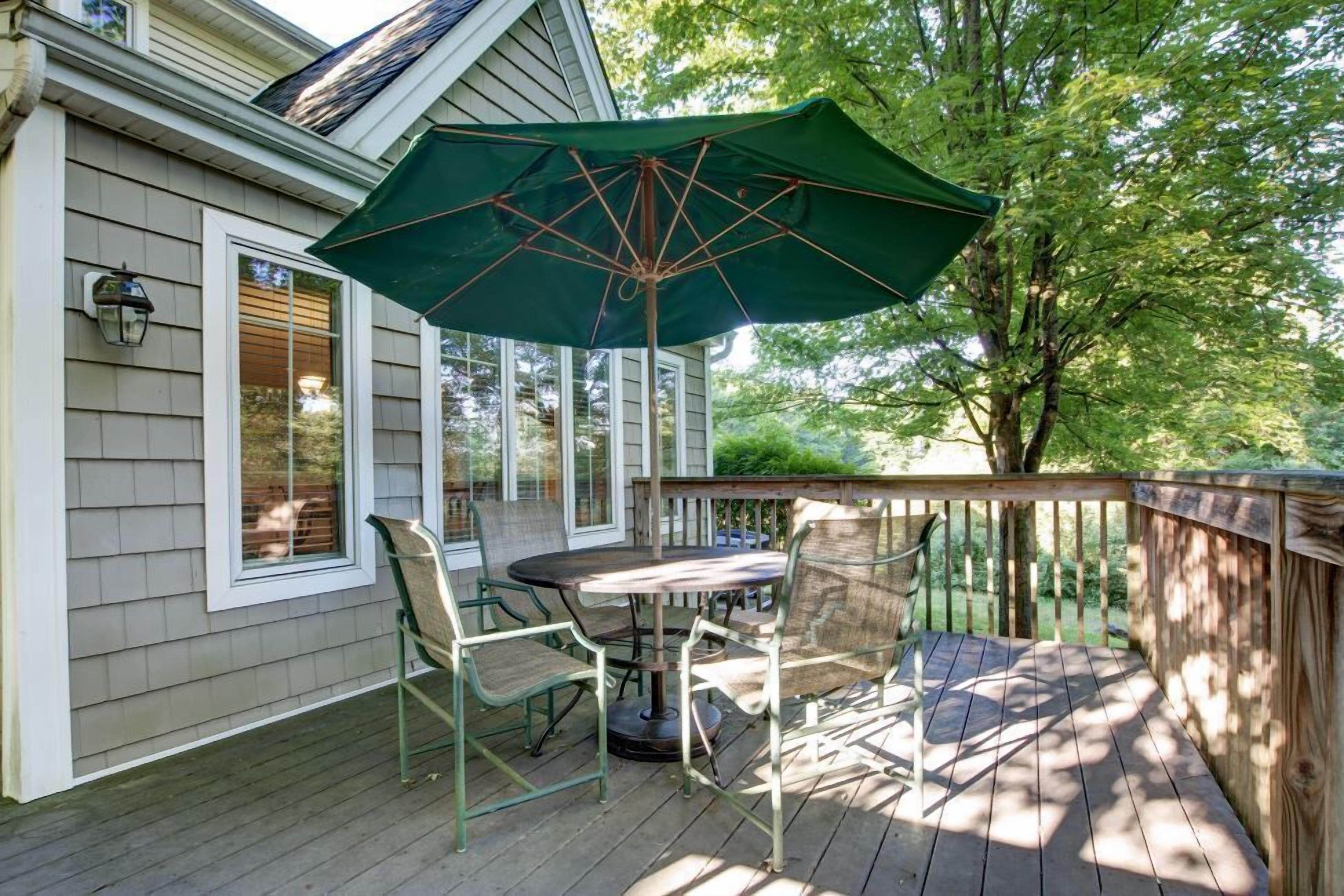 A wooden deck with a table and chairs, an umbrella, and a railing.