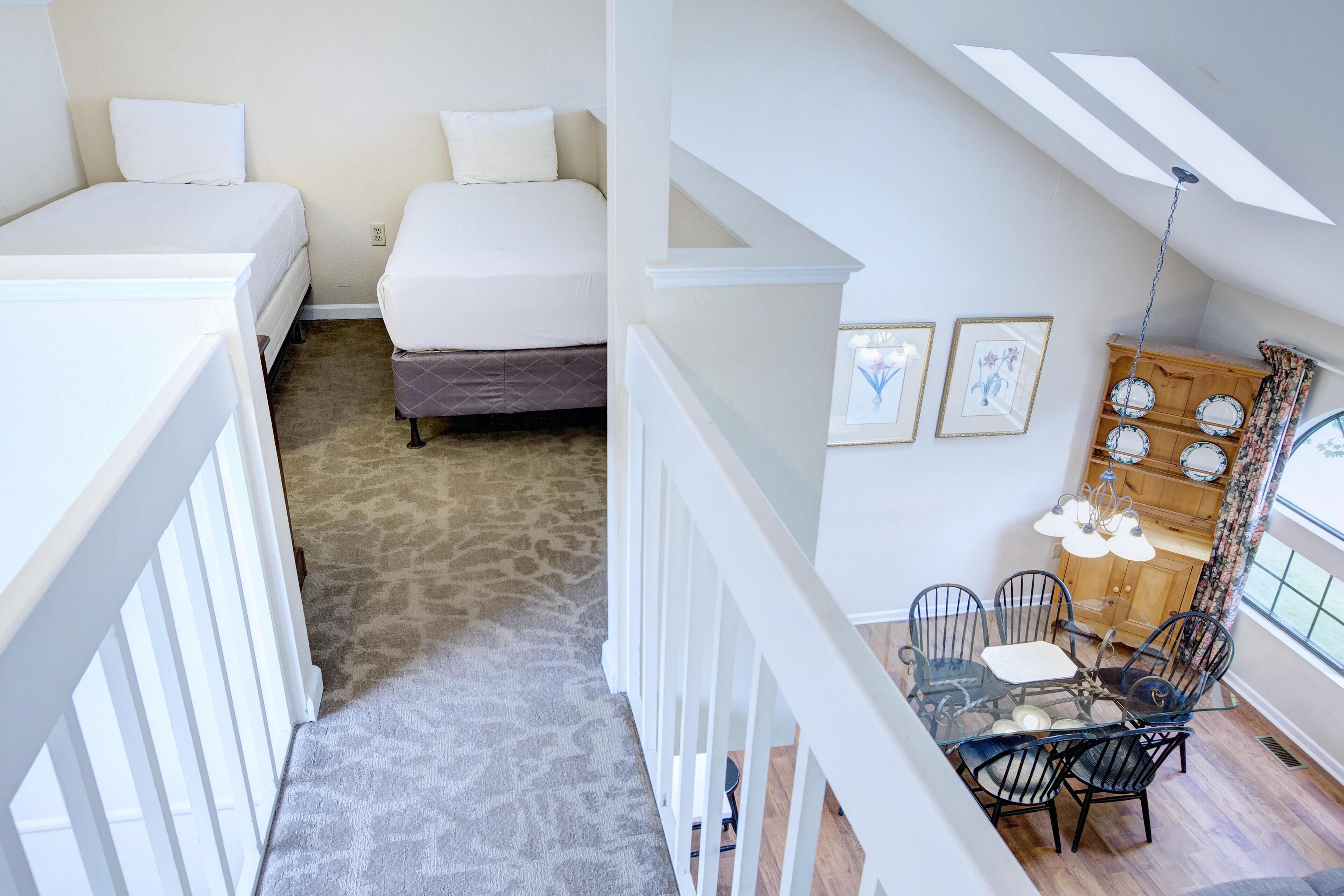 Une chambre avec deux lits, un coin repas comprenant une table et des chaises, et une vue sur l’extérieur par une fenêtre.