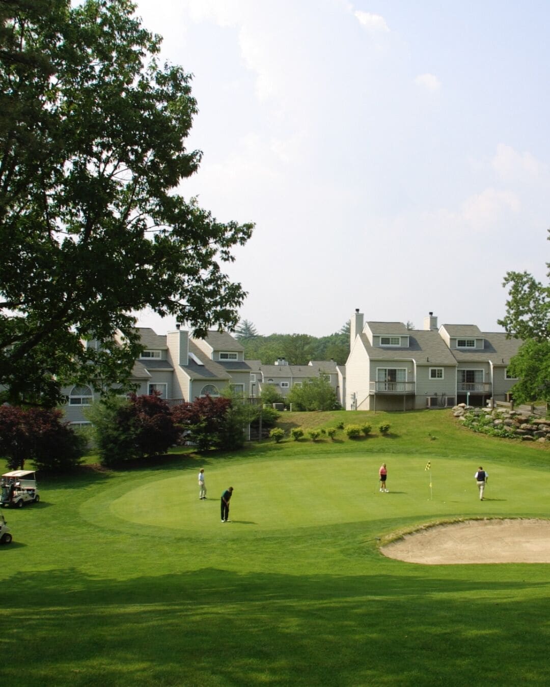 A golf course with a clubhouse and residential buildings in the background.