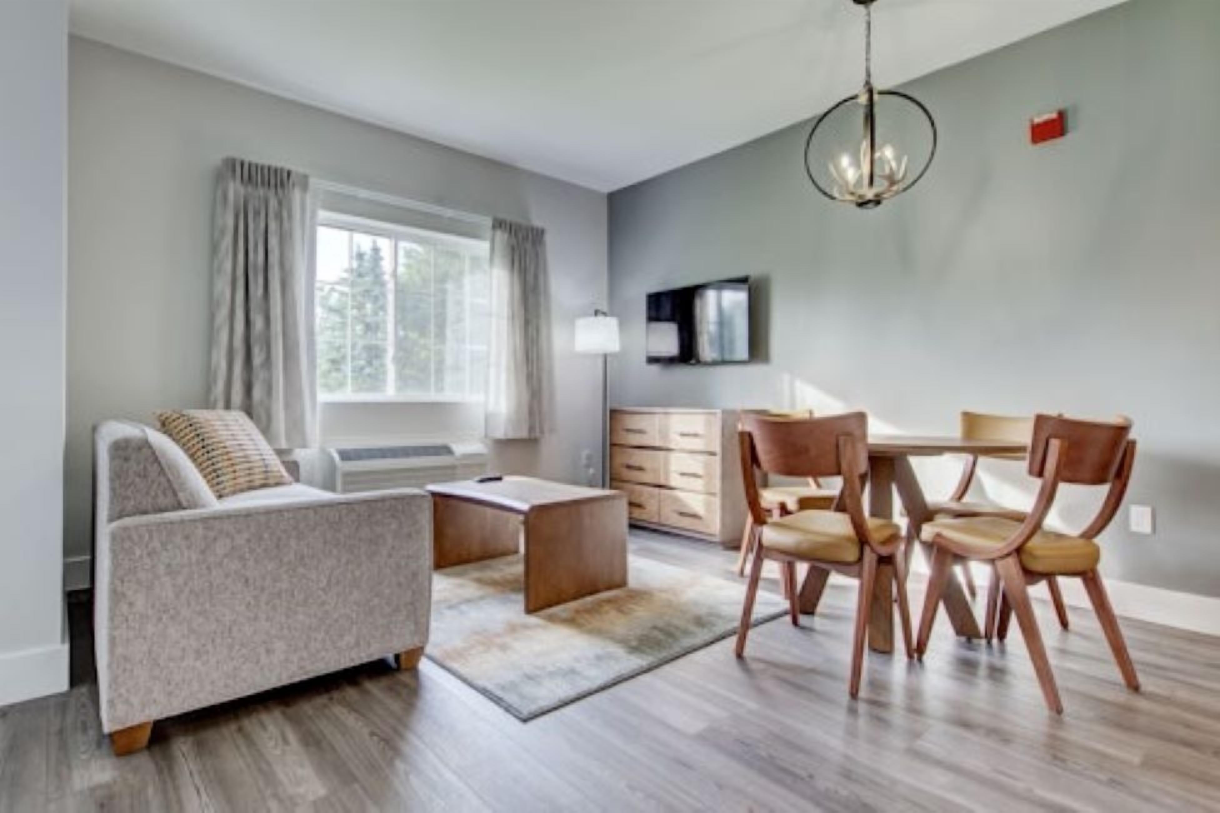 En moderne stue med sofa, sofabord og spisebord med stole.
