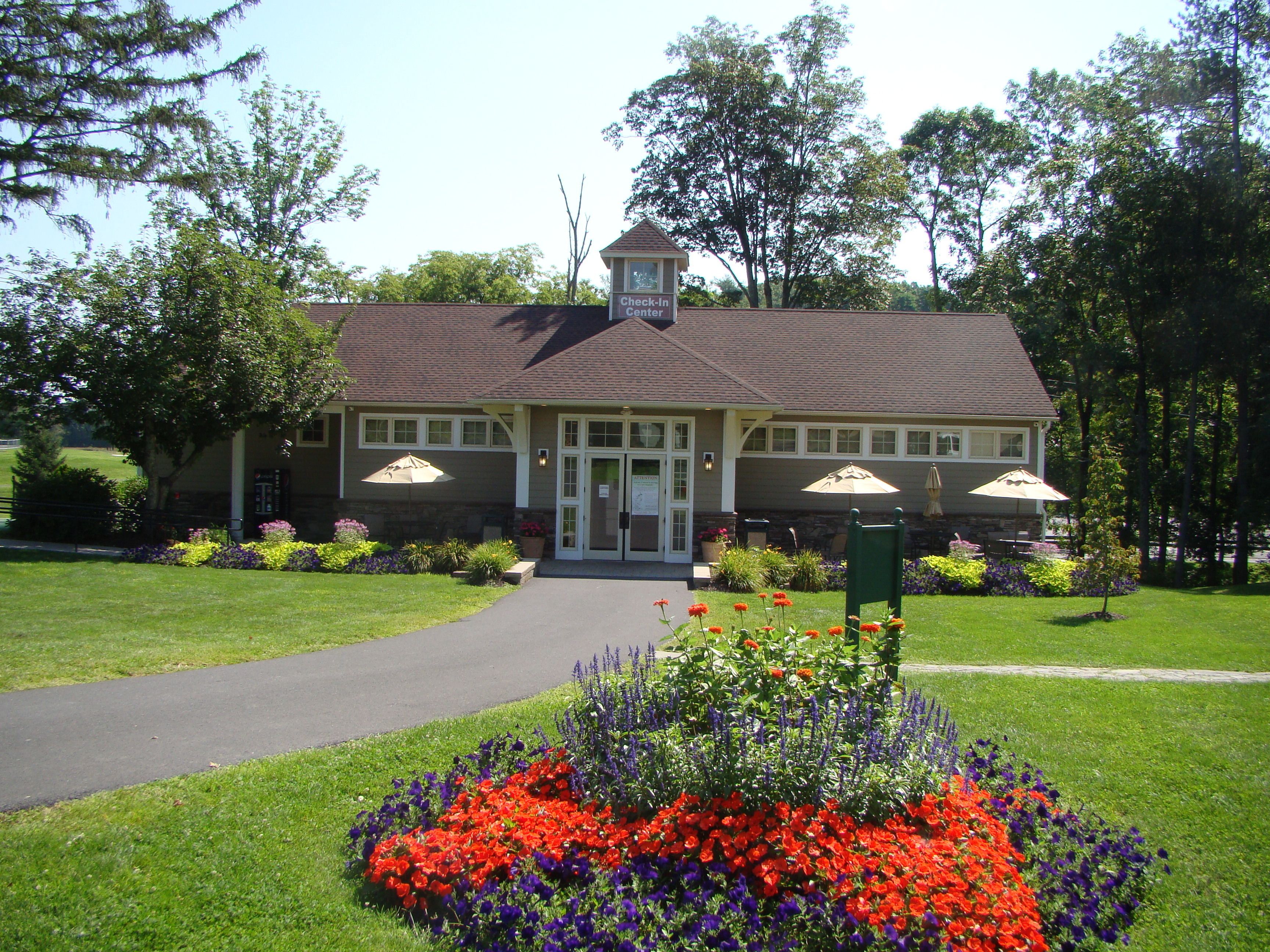 A lodge with a check-in center, a paved driveway, and a flower bed with red and purple flowers.