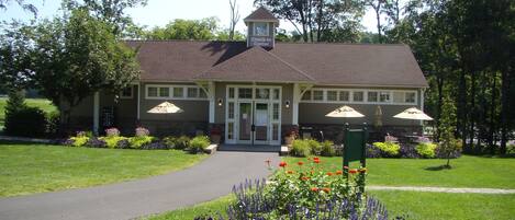 A lodge with a check-in center, a paved driveway, and a flower bed with red and purple flowers.