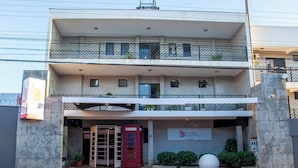 A two-story building with a reception area, a red telephone booth, and a sign for the Londres Royal Hotel. - Londres Royal Hotel (Londrina)