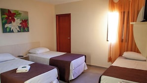 A hotel room with two single beds, a painting of flowers on the wall, a wooden door, and a window with curtains. - Londres Royal Hotel (Londrina)