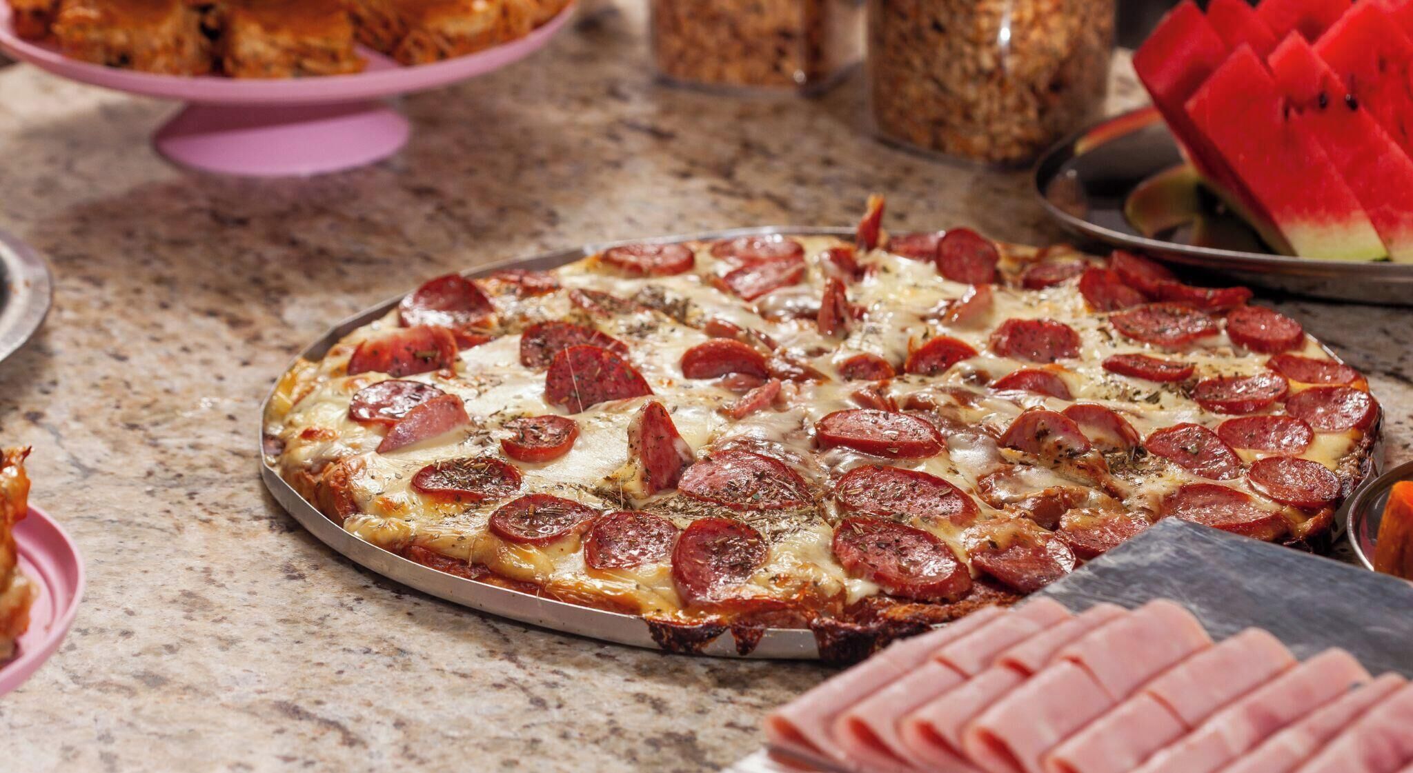 A pizza with pepperoni slices on a metal tray.
