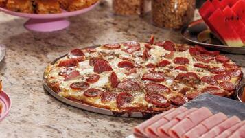 A pizza with pepperoni slices on a metal tray.