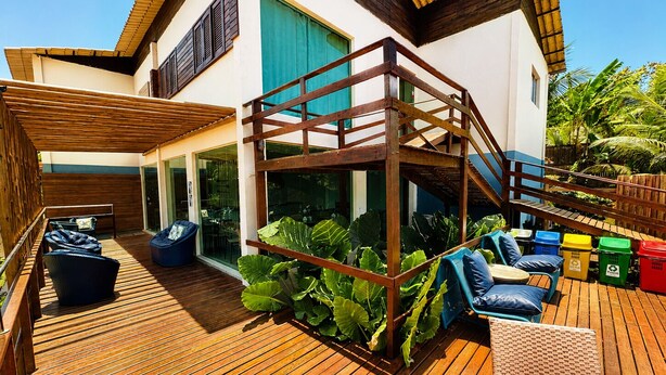 A wooden deck with outdoor seating, a staircase, and lush greenery. - Pousada Estrela Lunar Noronha by Alto da Ilha (Fernando de Noronha)