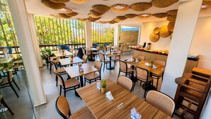 A restaurant with multiple tables and chairs, large windows, and a ceiling with woven light fixtures. - Pousada Estrela Lunar Noronha by Alto da Ilha (Fernando de Noronha)