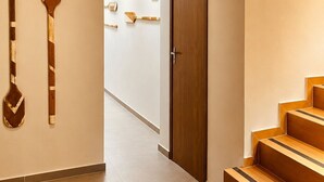 A modern interior with a wooden staircase, a hallway with wall-mounted paddles, and a door. - Pousada Estrela Lunar Noronha by Alto da Ilha (Fernando de Noronha)