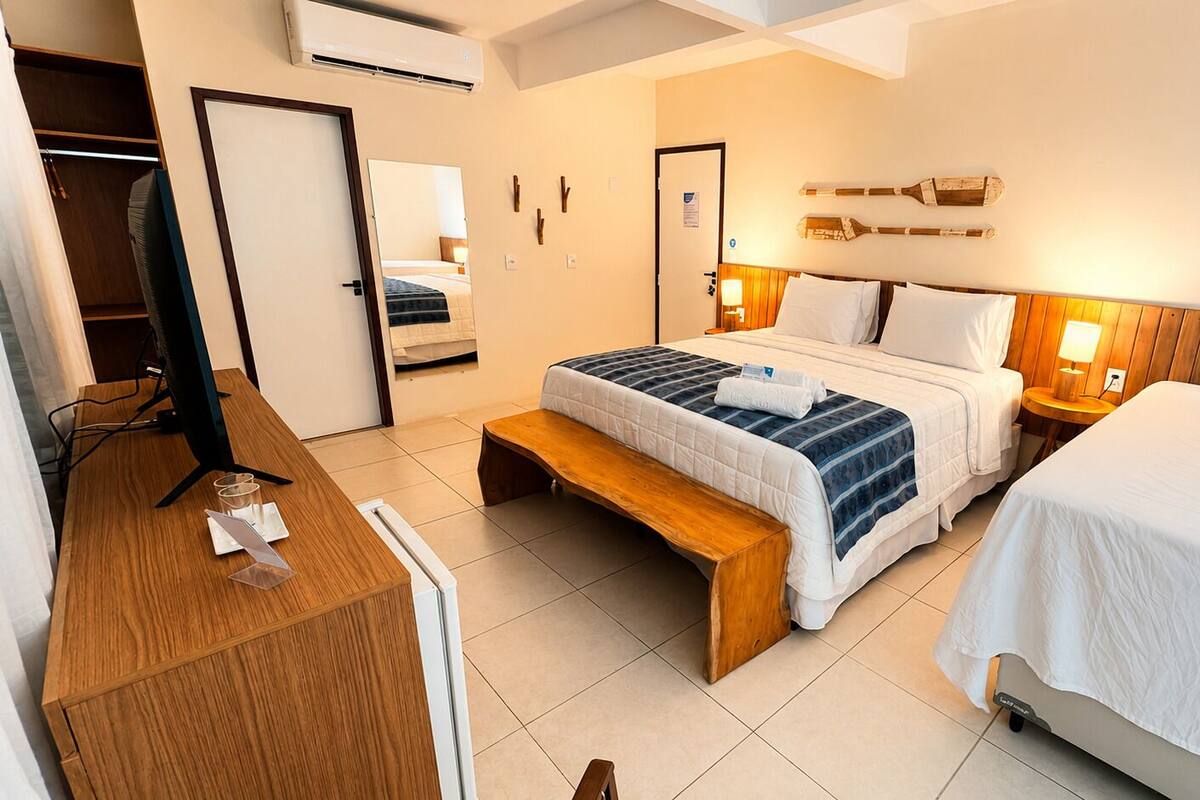 Ein Hotelzimmer mit Bett, Nachttischen, Schreibtisch, Stuhl, Bank und Kleiderschrank.