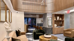 Un lobby moderno con un mostrador de recepción, zona de estar y una pared decorativa con un cartel enmarcado.