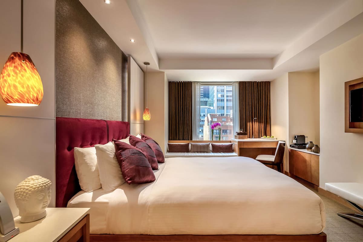 Ein Hotelzimmer mit einem großen Bett, einem Schreibtisch und einem fenster mit Vorhängen.