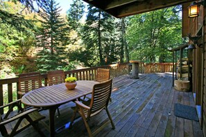 Relax on the deck surrounded by lush forest views and enjoy a meal at the round table.