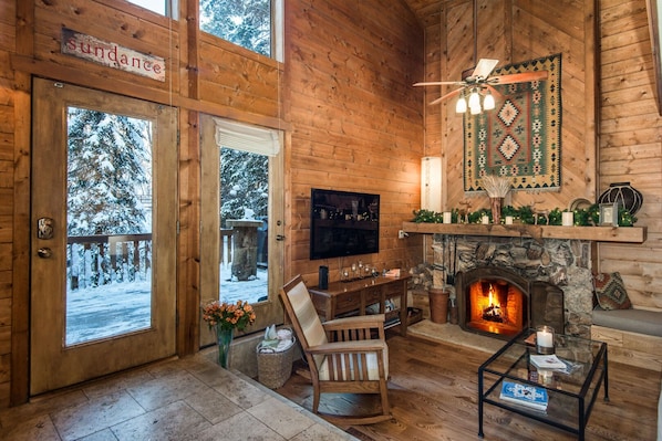 Cozy cabin with a stone fireplace, comfortable seating area, and TV.