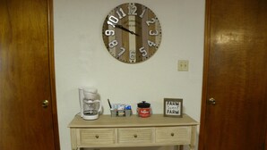 A wooden desk with a coffee maker, a jar of Folgers coffee, and a sign that says "FARM Sweet FARM".