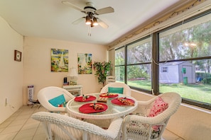 A dining area with wicker chairs, a round table, and a view of the outdoors. - Waterfront Deck & Private Dock! Rainbow River Home (Dunnellon)
