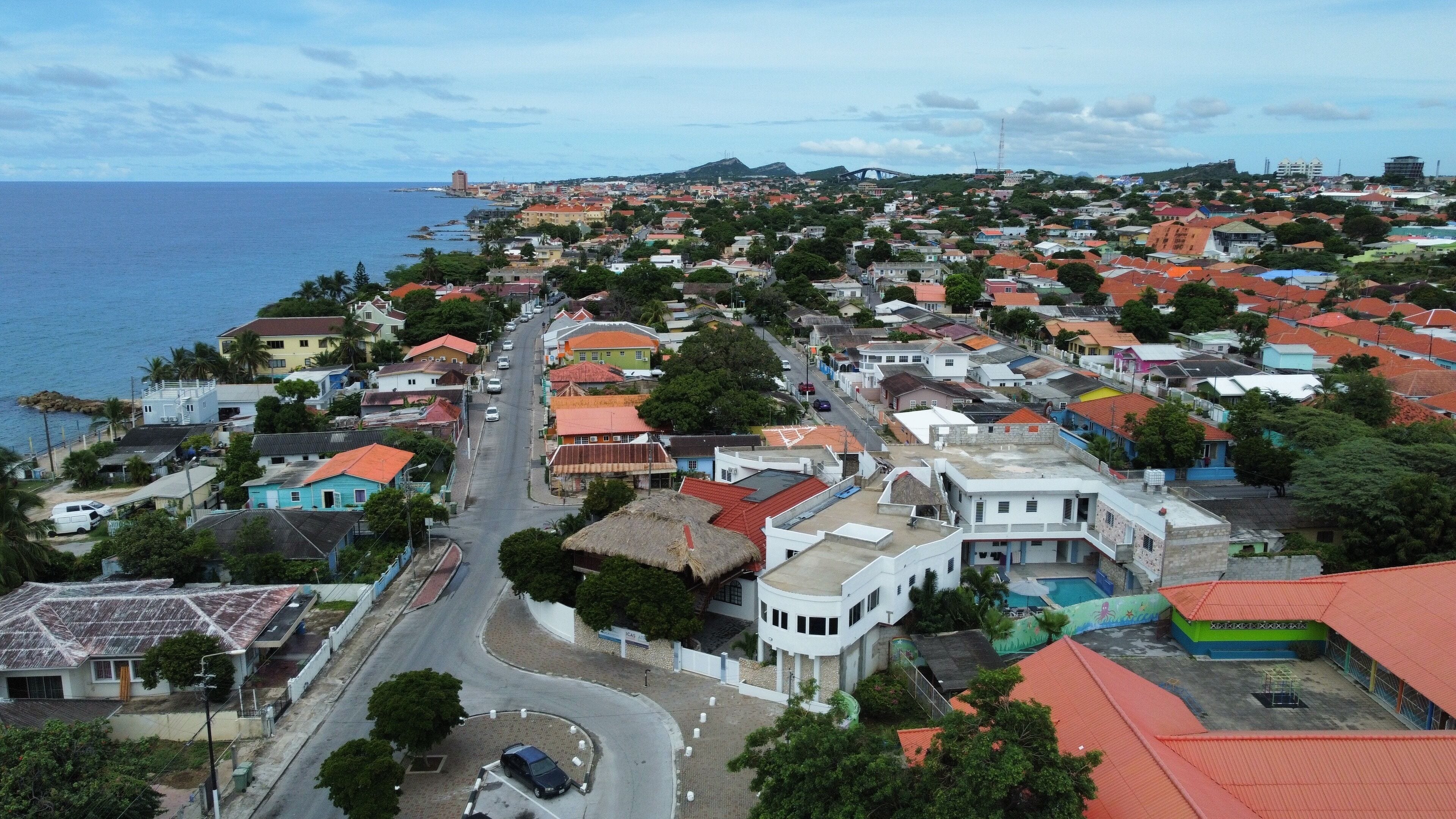A coastal town with a mix of residential buildings and a prominent white structure with a curved roof.