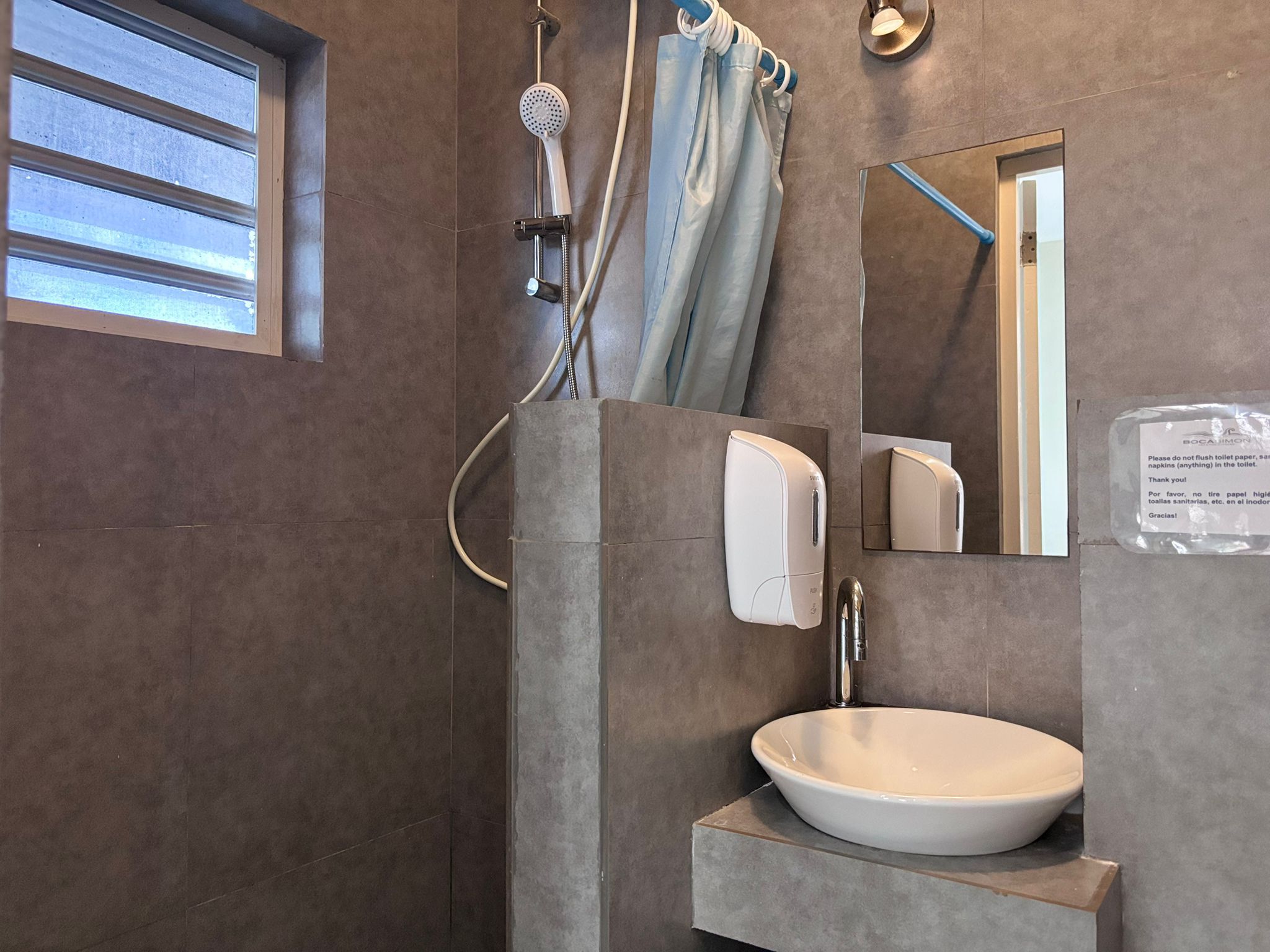 A bathroom with a large mirror, a sink, and a shower area.