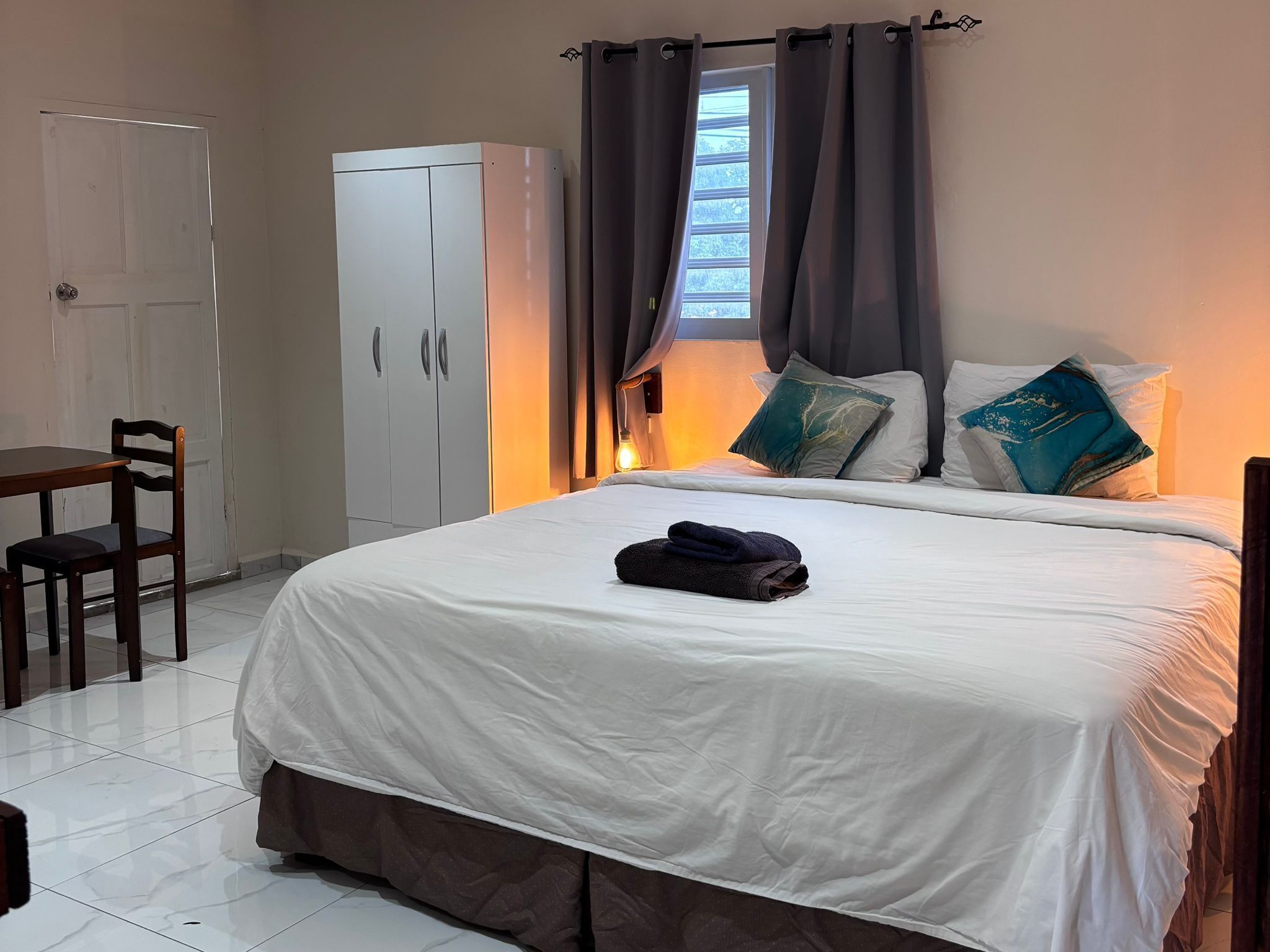 A hotel room with a bed, a wardrobe, a desk, and a chair.